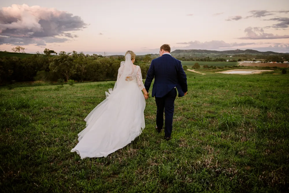 A wedding couple crossing a field at Lilydale Estate, 9Dorf Farms.