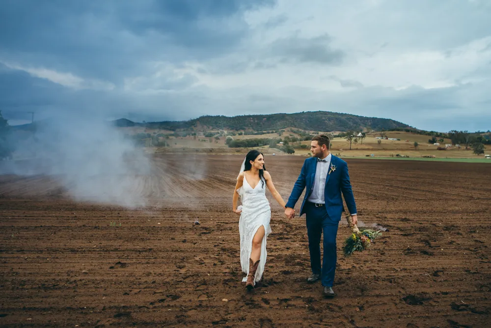 A wedding couple crossing a field, hand-in-hand, at Lilydale Estate, 9Dorf Farms.